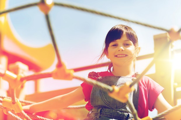 happy little girl climbing on children playground